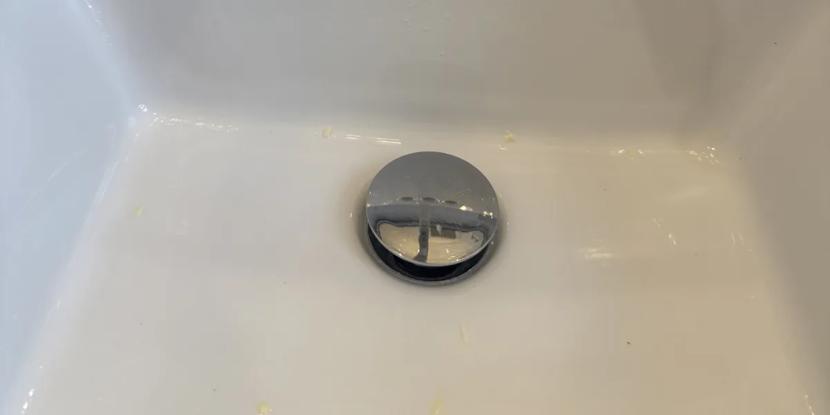 Chrome pop-up drain in a white bathroom basin after the branch line was cleared on a Milton call