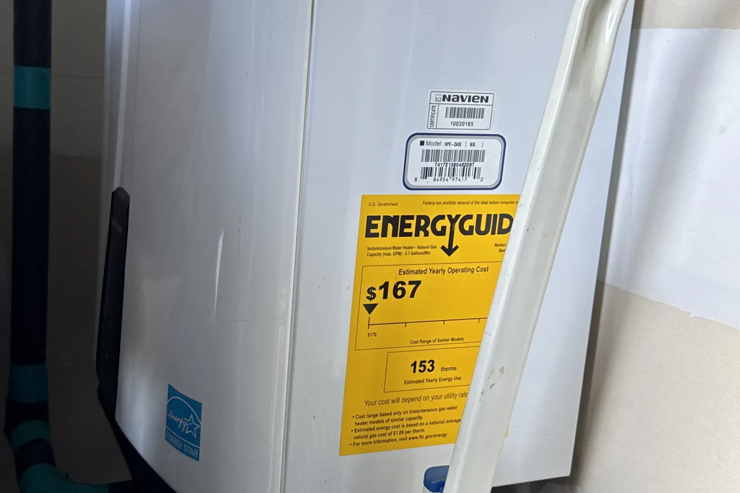 Wall-mounted Navien tankless water heater with its EnergyGuide label, serviced on a Quincy call