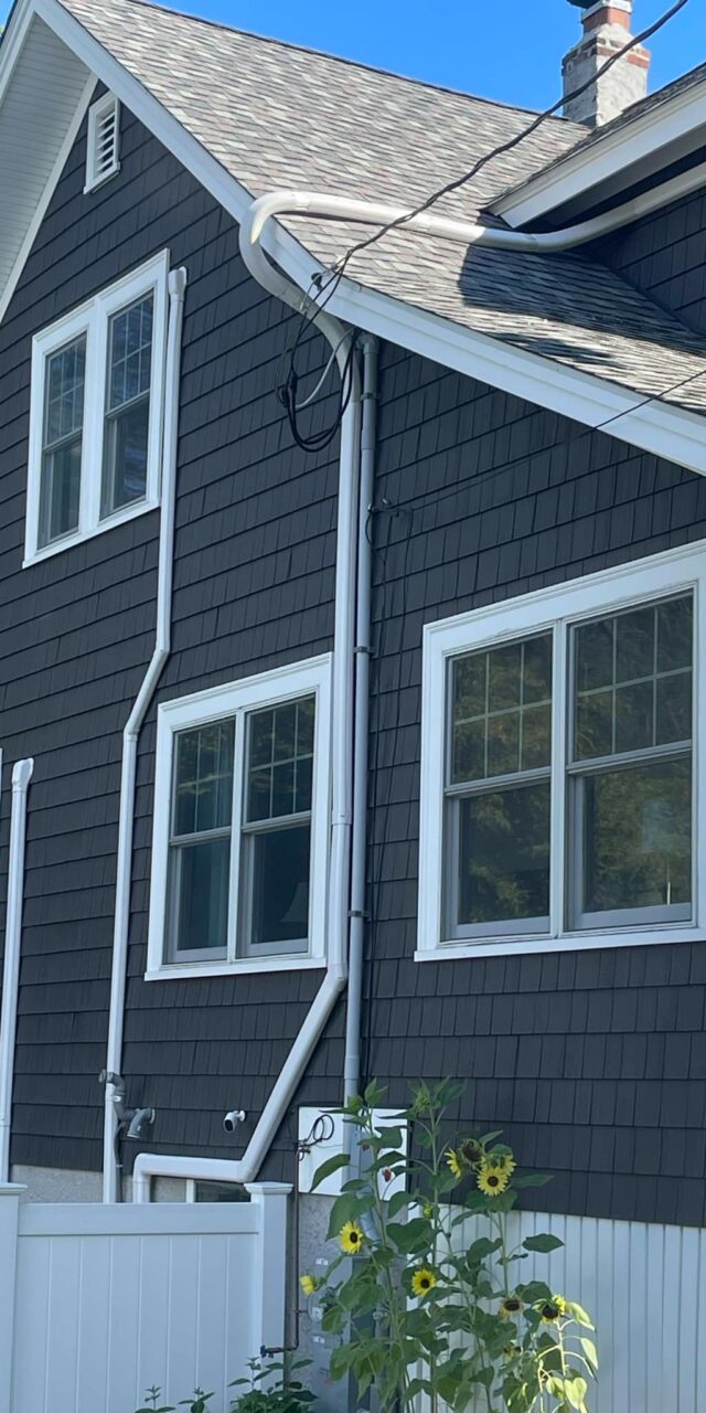 Exterior of a home showcasing energy-efficient upgrades with a heat pump installation by Johnson Bros. Plumbing & Drain Cleaning in Quincy, MA.